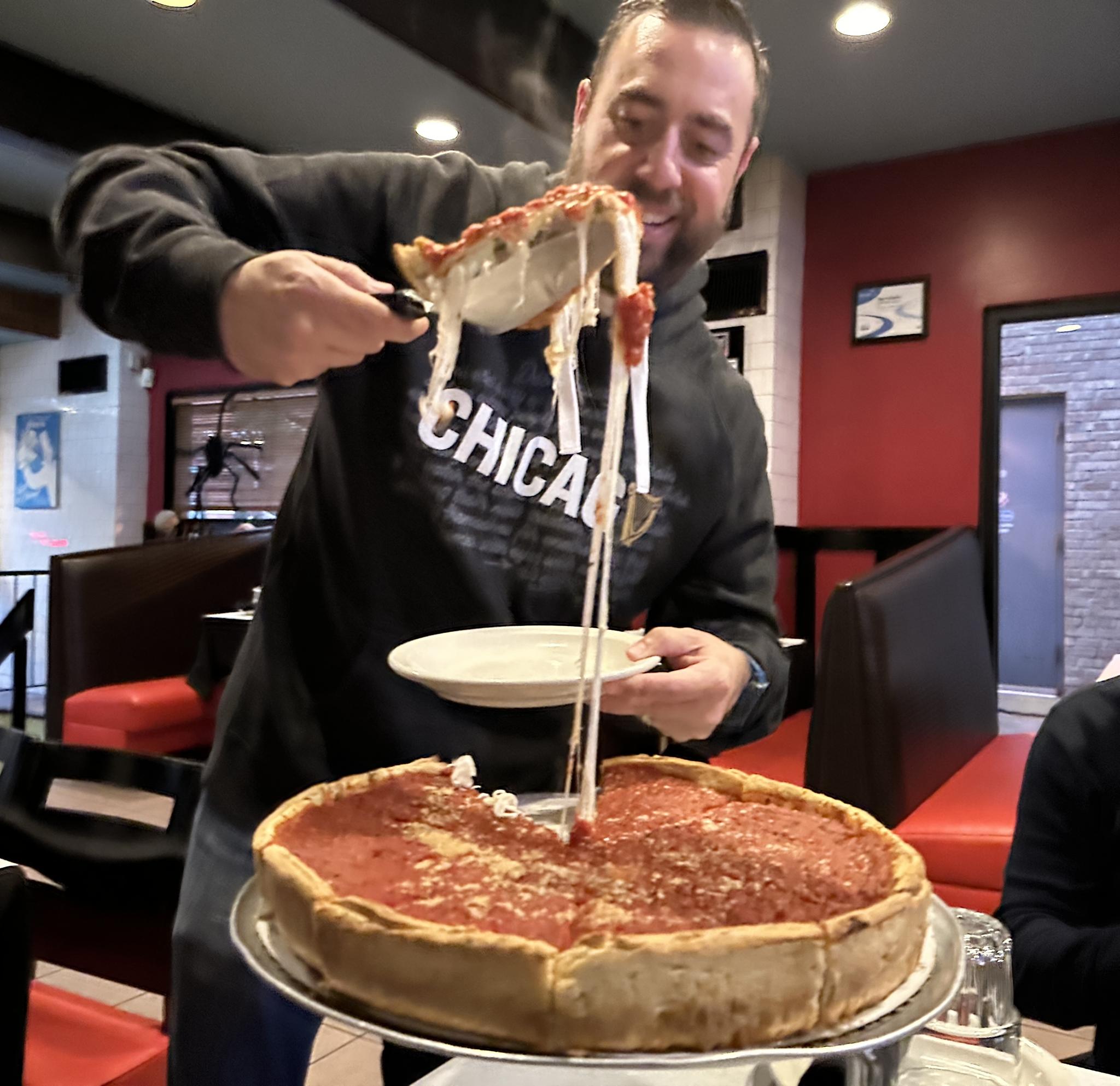 A slice of Chicago stuffed pizza pulled from the pan, showing the second sheet of dough over the cheese