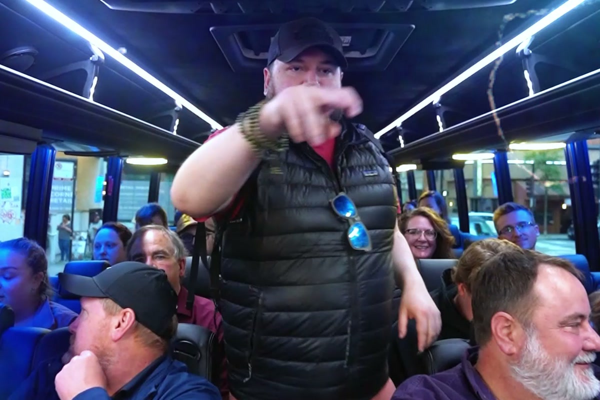 A corporate group riding a private tour bus between Chicago pizzerias